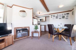 a living room with a television and a table and chairs at Dog Friendly Lovely Caravan by Beach Prestatyn N Wales 6 Berth Read full Host details before booking Mon in to Fri out Fri in to Mon out Mon to Mon Fri to Fri ONLY in Prestatyn