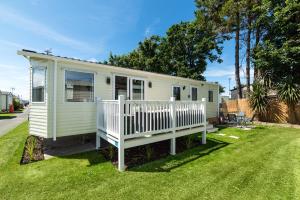 a tiny house with a white fence in a yard at Dog Friendly Lovely Caravan by Beach Prestatyn N Wales 6 Berth Read full Host details before booking Mon in to Fri out Fri in to Mon out Mon to Mon Fri to Fri ONLY in Prestatyn