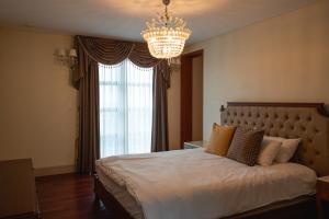 1 dormitorio con 1 cama grande y lámpara de araña en ArdenHill Resort & Golf, en Jeju