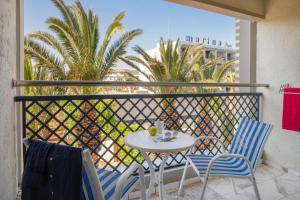 a table and chairs on a balcony with palm trees at Sol Marina Beach Crete in Gouves