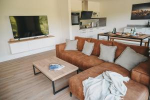 ein Wohnzimmer mit einem braunen Sofa und einem Tisch in der Unterkunft Ferienhaus Heimathafen am Diemelsee, Willingen, Winterberg in Diemelsee