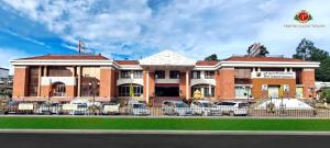 un bâtiment avec des voitures garées devant lui dans l'établissement Hotel Preethi Classic Towers, à Ooty