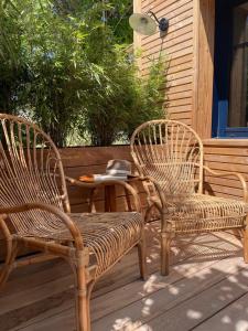 2 Korbstühle und ein Tisch auf einer Veranda in der Unterkunft Le Homard Bleu in Saint-Trojan-les-Bains