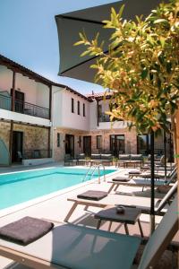 une piscine avec des chaises longues et un bâtiment dans l'établissement IADES suites, à Afytos