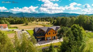 - une vue aérienne sur une maison avec une cour dans l'établissement Wonder Home - Apartamenty Halo Karkonosze z ogrodem, sezonowym basenem, placem zabaw i widokiem na Śnieżkę - zlokalizowane blisko Karpacza, à Mysłakowice