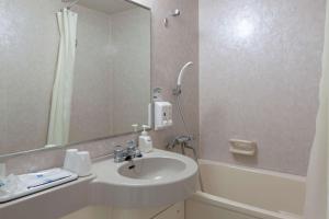 a bathroom with a sink and a mirror and a tub at Comfort Hotel Tendo in Tendo