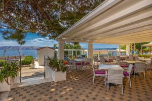 un patio con mesas y sillas y vistas al océano en Rocky Beach Rooms, en Novi Vinodolski