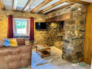 - un salon avec un canapé et une cheminée en pierre dans l'établissement Hafan Hedd - Romantic Rural Retreat in Pembrokeshire, à Solva