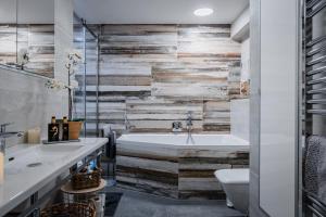a bathroom with a wooden accent wall and a tub at Penthouse Letňanské zahrady in Prague +27 photos