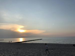 Ein kleiner Junge, der bei Sonnenuntergang am Strand spazieren geht. in der Unterkunft Niebieski in Rewal