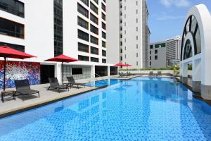 a swimming pool with chairs and umbrellas on a building at BelAire Bangkok Sukhumvit in Bangkok