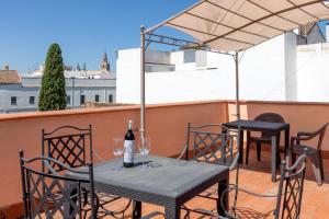 uma mesa e cadeiras numa varanda com uma garrafa de vinho em Puerta San Esteban em Sevilha
