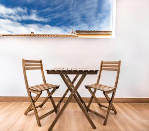 a wooden table and two chairs in front of a wall at HOMEABOUT LA MERCED Studios in Málaga