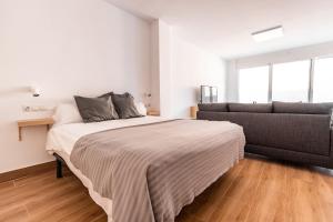 a bedroom with a bed and a couch at HOMEABOUT LA MERCED Studios in Málaga
