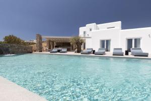 a swimming pool with chairs and a villa at Blue Eye Grand Villa Mykonos in Kalafatis