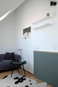 ein Wohnzimmer mit einem blauen Sofa und einem Tisch in der Unterkunft Bright + Cozy Dachgeschoß Maisonette im Zentrum in Bregenz