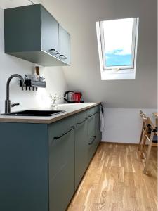 a kitchen with blue cabinets and a window at Bright + Cozy Dachgeschoß Maisonette im Zentrum in Bregenz