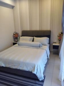 een slaapkamer met een groot bed met witte lakens en kussens bij Hyve Soho Suite - Netflix in Cyberjaya