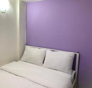łóżko z białymi poduszkami i fioletową ścianą w obiekcie J mini hotel & house w Seulu