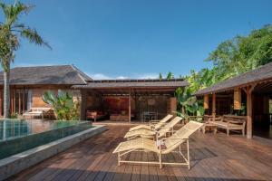 an outdoor deck with chairs and a swimming pool at Secret River Villa in Kerobokan