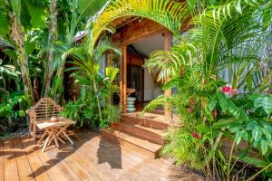 a house with a wooden porch with trees and plants at Secret River Villa in Kerobokan