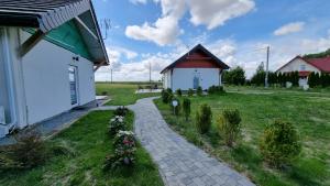 a small house with a brick path next to a field at Agroturystyka u Karoliny in Sarbinowo