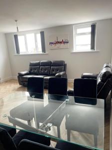 ein Wohnzimmer mit einem Glastisch und Ledersofas in der Unterkunft Smith Stayz Apartments in Blackpool