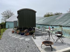 a patio with a table and chairs and a building at Puddle Duck Shepherd Hut in Launceston