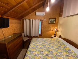 a bedroom with a bed and a dresser and a television at Chalé Estilo Alemão - Centro de Canela in Canela