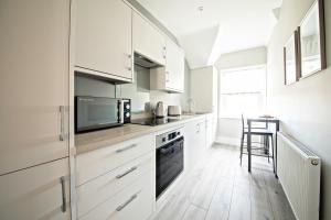 a kitchen with white cabinets and a stove top oven at The Loft Apartment, 8 Granville Road in Harrogate
