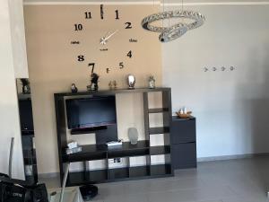 a living room with a tv and a clock on the wall at Da Lumi Relax in Lanzo Torinese