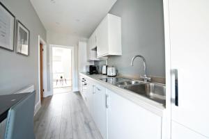 a kitchen with white cabinets and a stainless steel sink at The Loft Apartment, 8 Granville Road in Harrogate