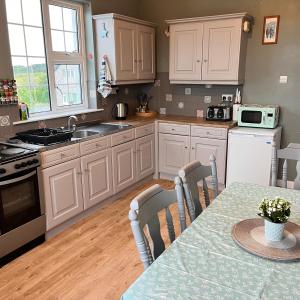 a kitchen with white cabinets and a table with chairs at Wild Atlantic Stay Cottage in Galway