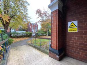 a sign on the side of a brick building with a caution sign at Spacious Victorian Double Room 2 in Doncaster