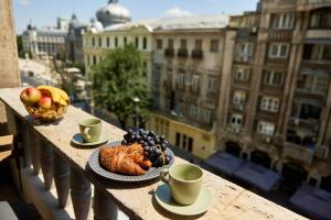 a plate of food on a balcony with cups of coffee at Voguish in Bucharest