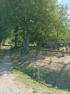 ein Park mit einer Bank, einem Zaun und Bäumen in der Unterkunft Maisonnette en campagne "Le Rocher" in Vibraye