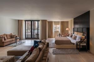 ein großes Hotelzimmer mit einem Bett und einer Couch in der Unterkunft Rhactus Hotel, New Alamein in El-Alamein