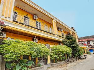 a yellow building with bushes in front of it at OYO 91418 Kantil Homestay Syariah in Sunggal