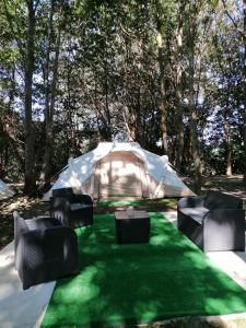 a tent with chairs and a green lawn at La Finca - Campamento en la Naturaleza in Carranceja