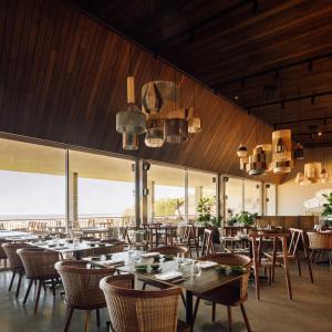 uma sala de jantar com mesas, cadeiras e janelas em Immerso Hotel, a Member of Design Hotels na Ericeira