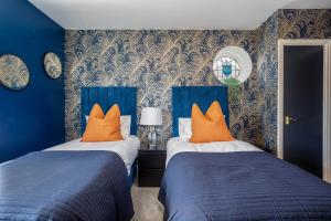 two beds in a bedroom with blue walls and orange pillows at Empress Hall Blackpool by Charles Alexander Short Stay - Sleeps 20 in Blackpool