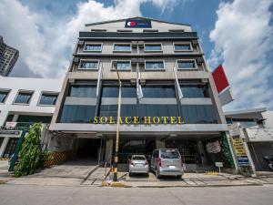 un bâtiment avec deux voitures garées devant lui dans l'établissement Solace Hotel, à Manille