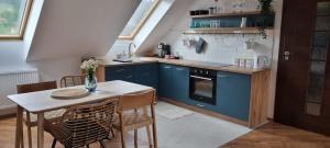 a kitchen with blue cabinets and a table and chairs at Apartament w centrum - Nasze poddasze in Ustrzyki Dolne