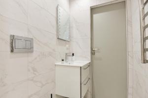 a white bathroom with a sink and a mirror at Apartamentai centre pas Lina in Nida