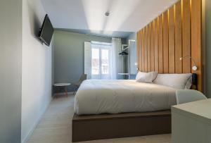 Schlafzimmer mit einem großen Bett mit einem Kopfteil aus Holz in der Unterkunft B&B HOTEL Madrid Centro Fuencarral 52 in Madrid