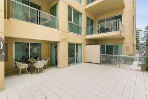 a large building with a patio with a table and chairs at Pier 108 Glenelg in Glenelg