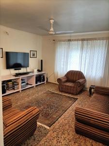 sala de estar con 2 sillas y TV de pantalla plana en Snow Leopard Lodge, en Srinagar
