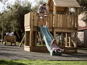 a man and a little girl on a slide in a playground at Contessina Hotel in Tsilivi