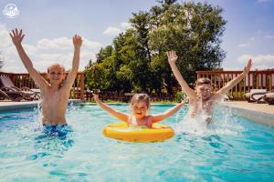 two boys and a girl in a swimming pool at Western Camp Resort in Zator