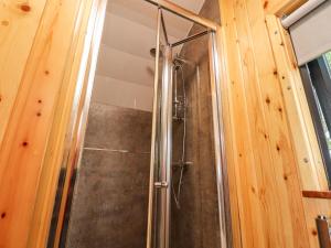 a shower in a bathroom with a wooden wall at Jackdaws Den in Lancaster